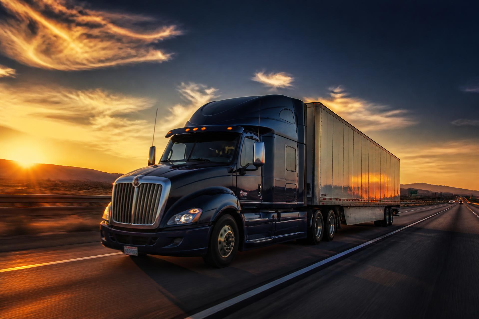 Semi truck driving on an American interstate at sunset